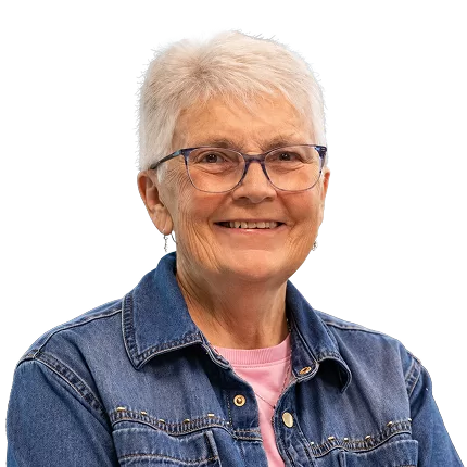 Friendly portrait of Sister Joan Atkinson, wearing a denim jacket over a pink shirt.